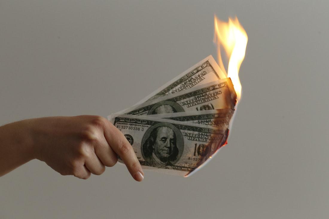 Ilustrasi uang yang terbakar sebagai peringatan risiko finansial