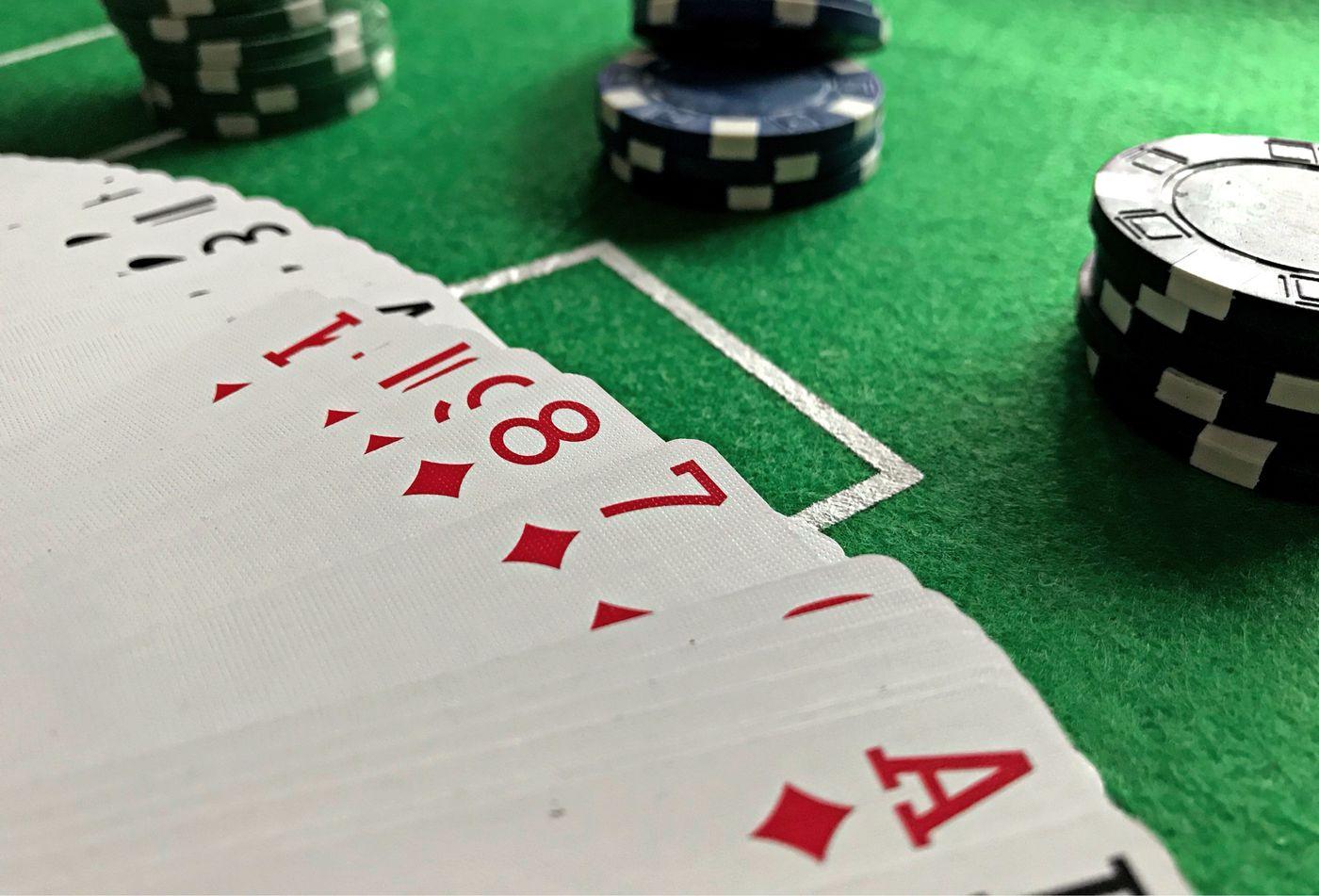 Kartu remi dan tumpukan chip poker di atas meja hijau